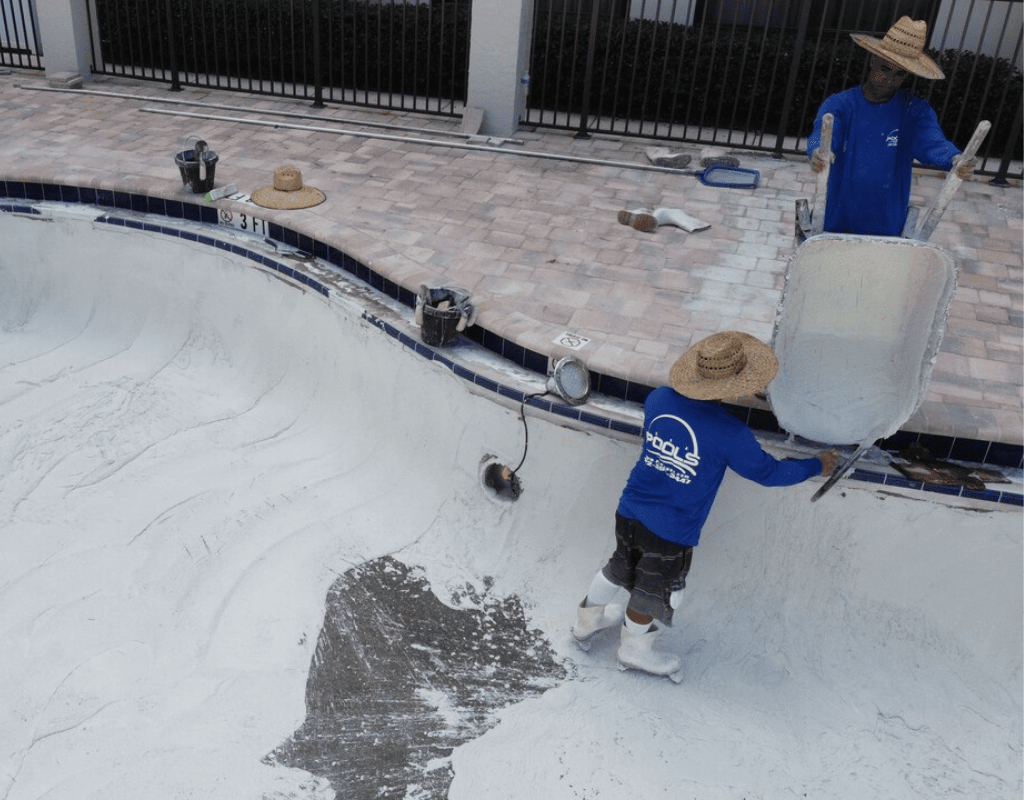 Technician kneeling and installing new tile coping on a pool deck adjacent to a home during professional pool repair by Pools USA in Port St. Lucie, FL.